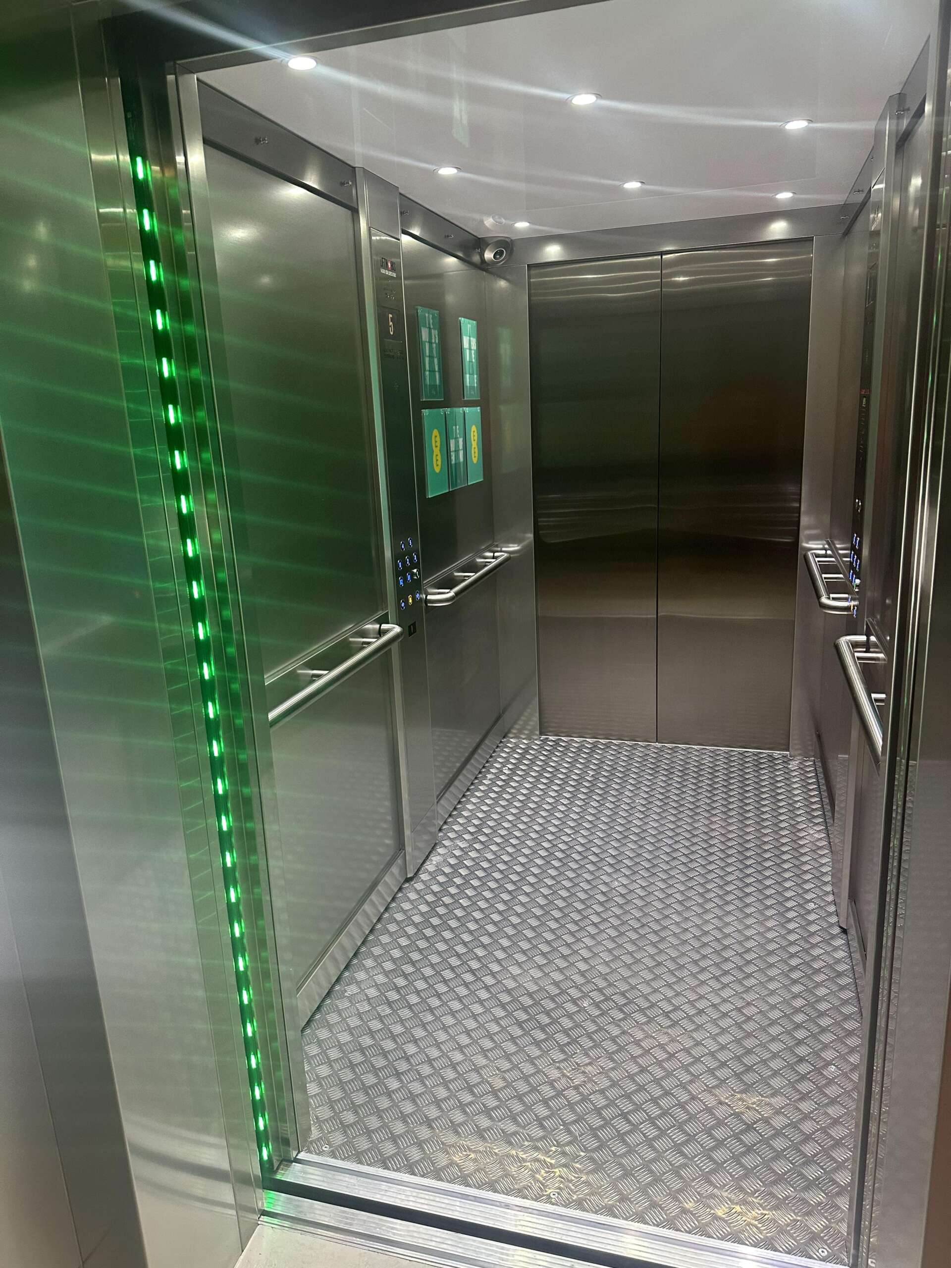 a metal elevator with green lights